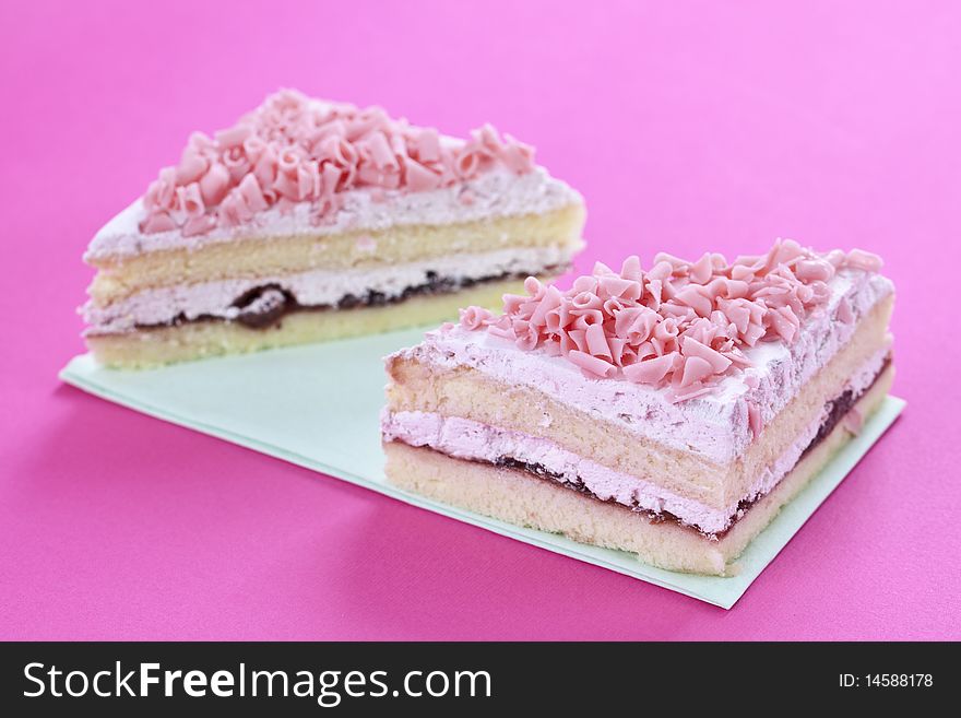 Close up of fresh sliced cake on pink table top