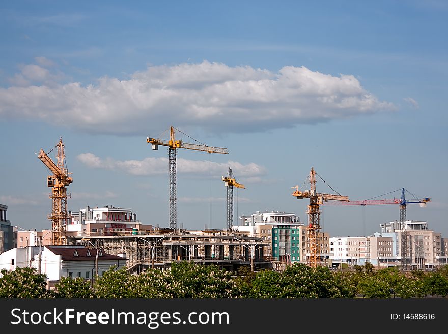 Building cranes panorama and bright blue sky with white clouds
