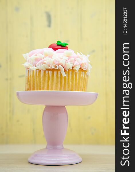 Strawberry cupcake with pink frosting on a dessert display stand pillar pedestal