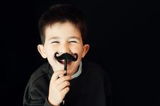 Happy Kid Posing With A Fake Moustache On Black Background Stock Images