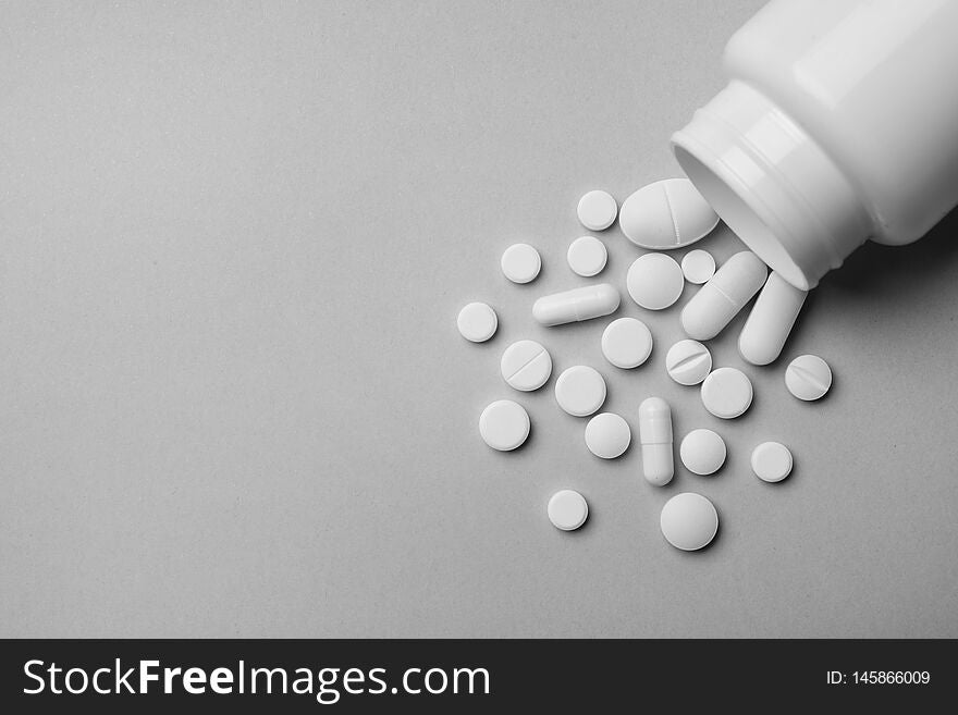 Bottle with different pills on grey background, flat lay