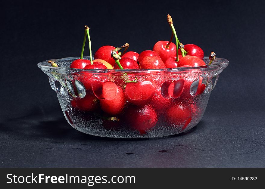 Red cherry fruits on black background.