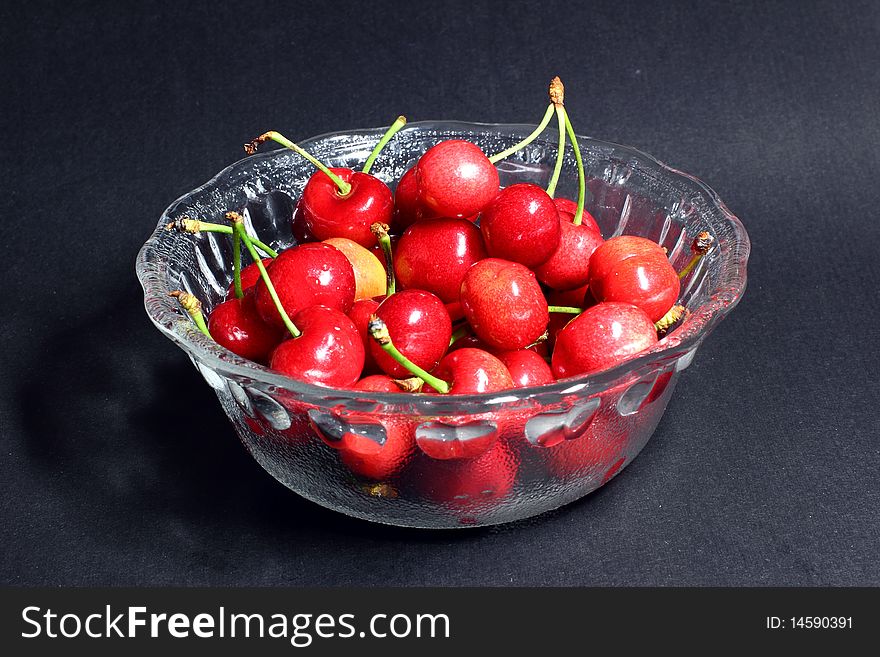 Red cherry fruits on black background.