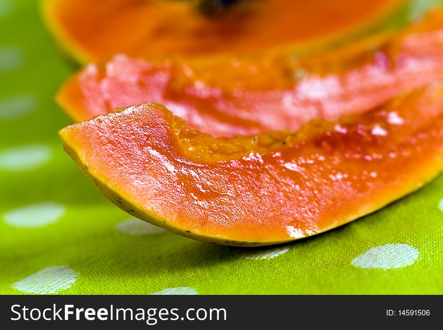 Cut up papaya fruit on green background