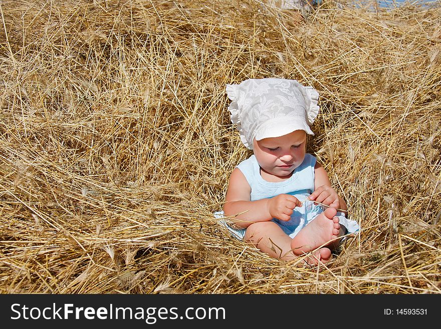 Cute toddler girl playing in haystack