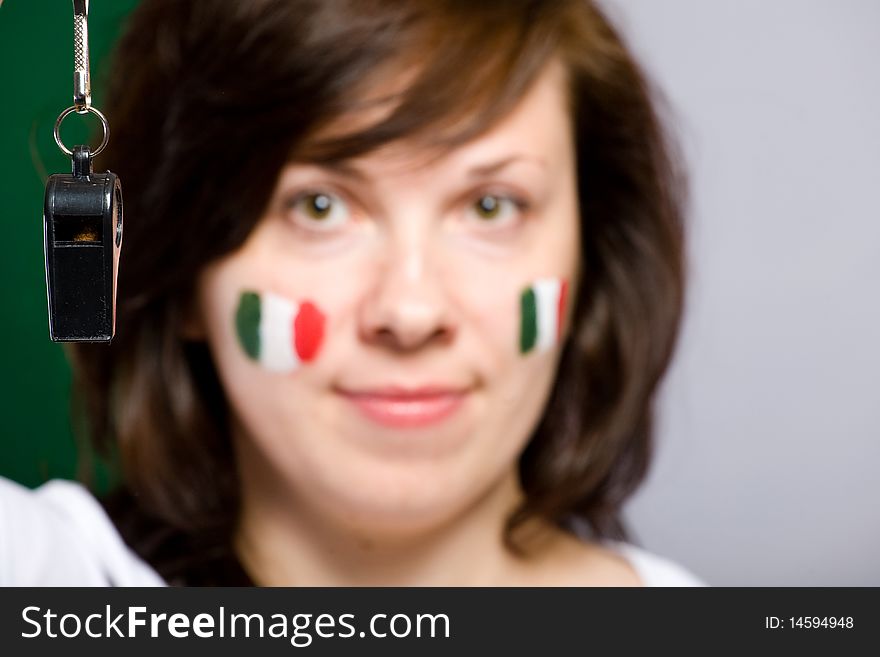 Black whistle on foreground with female face being blurres as background, italian flags painted on female cheeks. Black whistle on foreground with female face being blurres as background, italian flags painted on female cheeks