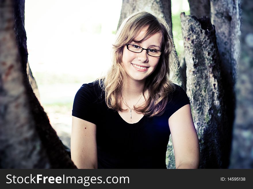 Portrait of a young girl sitting around trees. Portrait of a young girl sitting around trees