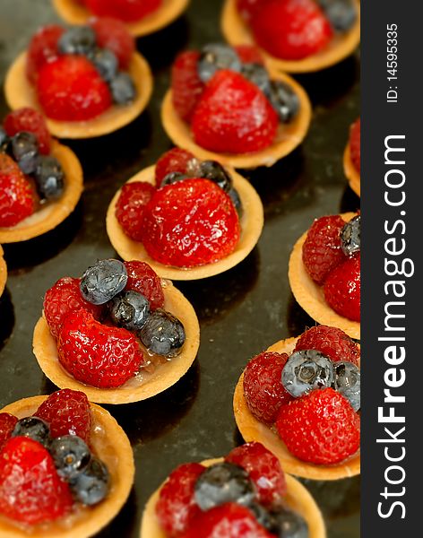 Strawberry and blueberry tarts are in rows.