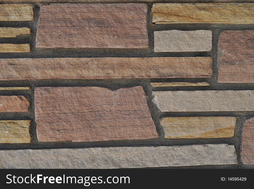 A brick wall with a multi-colored mosaic pattern. A brick wall with a multi-colored mosaic pattern.