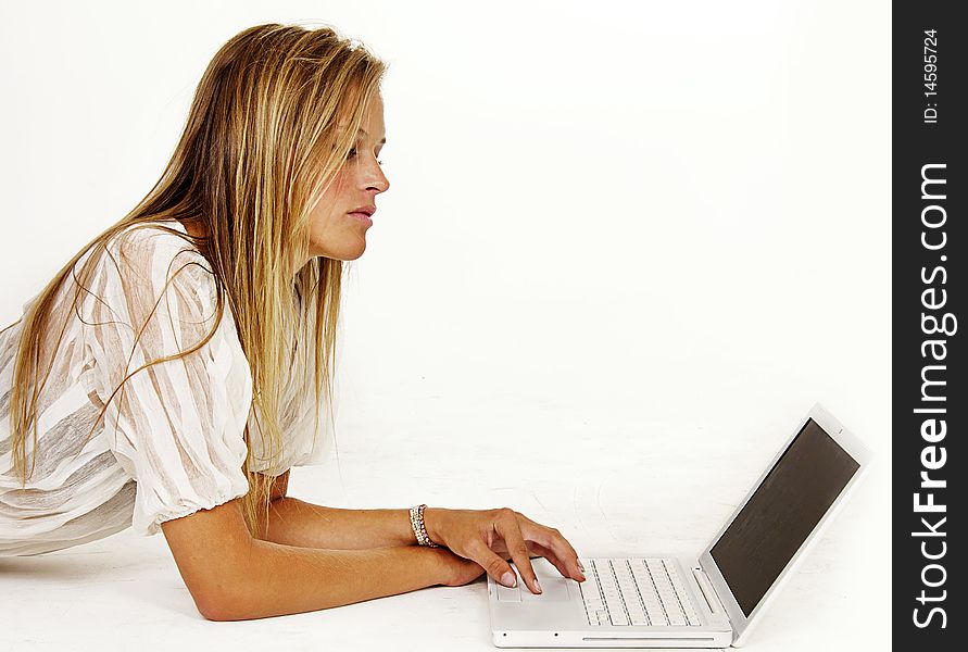 Pretty young woman while typing studying on laptop computer.  Isolated against white background. Pretty young woman while typing studying on laptop computer.  Isolated against white background.