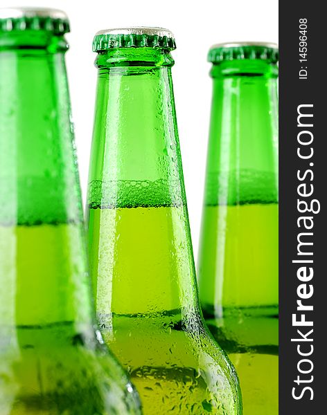 Three beer bottles with water drops on white