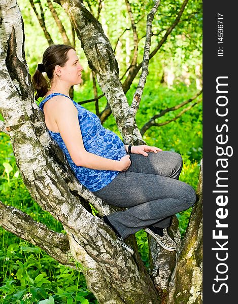 Pregnant young woman sitting on tree. Pregnant young woman sitting on tree
