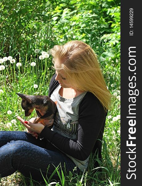 Blond girl playing with small black dog. Blond girl playing with small black dog