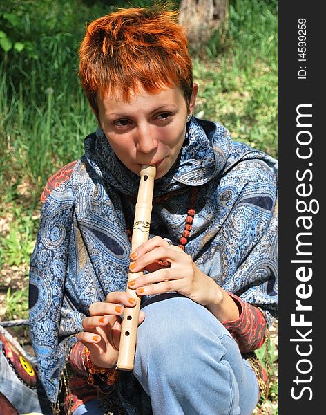 Young woman playing wooden reed on grass. Young woman playing wooden reed on grass