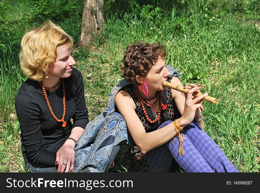 Two girls with wooden reed sit on grass. Two girls with wooden reed sit on grass