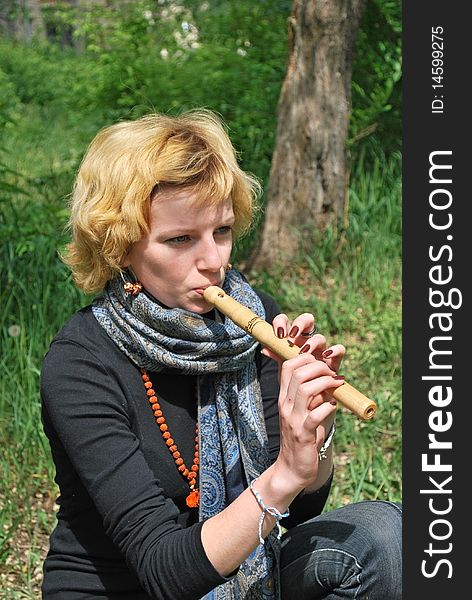 Young blond woman with wooden reed outdoor. Young blond woman with wooden reed outdoor