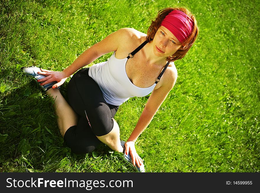 A young girl in a tracksuit sitting on the grass. A young girl in a tracksuit sitting on the grass