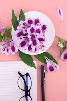 Fragrant Tea In A White Cup, Beautiful Flowers, A Pink Background, A Notebook With A Pen And Glasses Stock Photo