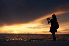 Silhouette Of Woman Alone At Water Edge, Enjoying Beautiful Seascape At Sunset. Royalty Free Stock Photo