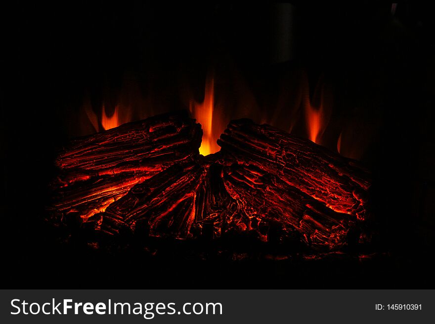 Wood burning in a fireplace at home. Close up  of burning firewood in the fireplace. Burning fireplace. Fire to keep warm. Firewood, charcoal, flames. Holiday Christmas concept. Cozy atmosphere.