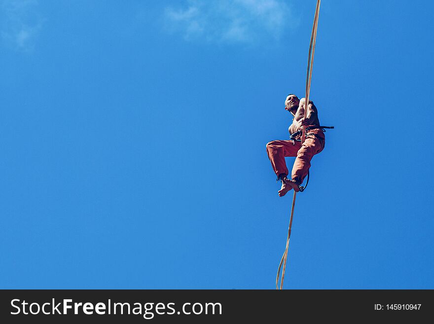 Man walking along high line rope on the blue sky background. Man walking along high line rope on the blue sky background