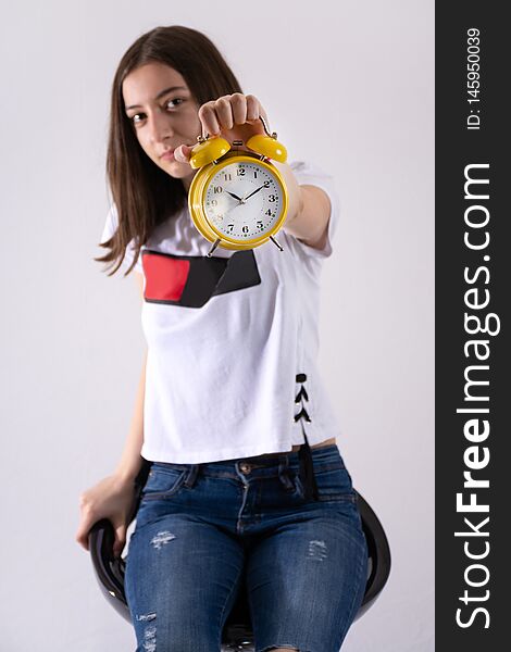 Young girl with retro clock in hand showing time on yellow clock isolated on white background