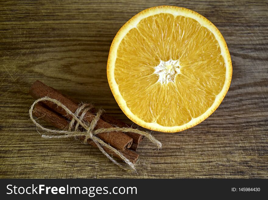 Ripe orange, Cinnamon sticks on wooden surface
