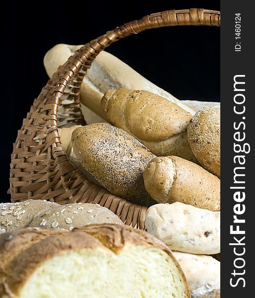 An assortment of breads in a basket with a black background. An assortment of breads in a basket with a black background