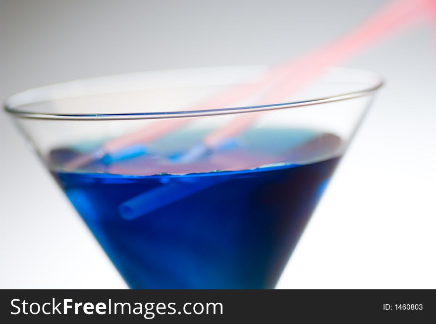 Close up shot of a blue cocktail with pink straws