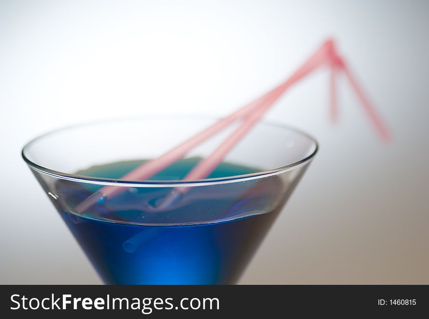 Close up shot of a blue cocktail with pink straws