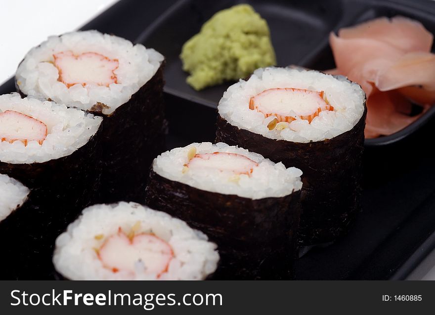 A close-up view of sushi on a plate with ginger slices and wasabi. A close-up view of sushi on a plate with ginger slices and wasabi