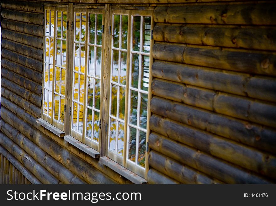 Fall Foliage Reflected In Window Of Log Home