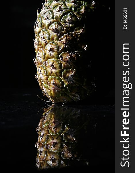 Pineapple on black background reflecting on black surface