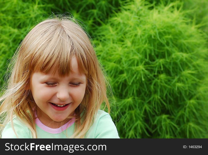 Girl in a garden having fun in front of green bush