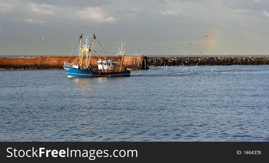 Fishing trawler bringing in the catch, with trailing gulls and a rainbow. Fishing trawler bringing in the catch, with trailing gulls and a rainbow