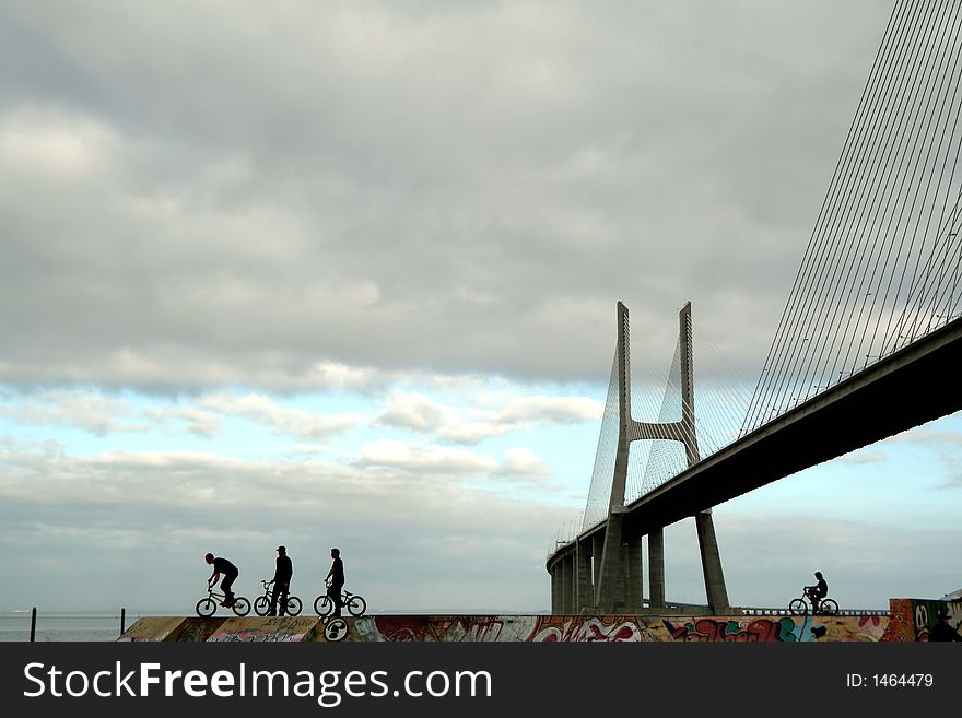 Silhouettes of active teens on BMX bike, urban extreme sports on park