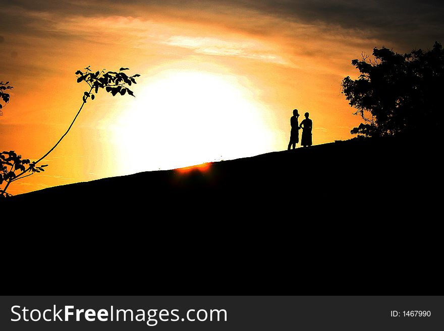 A silhouette of a couple standing against orange sunset (Venezuela). A silhouette of a couple standing against orange sunset (Venezuela)