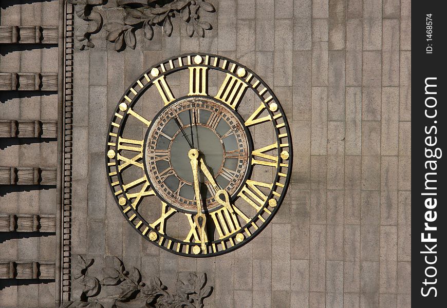 Antique Gold Clock on the face of an old building with ornate carvings. Antique Gold Clock on the face of an old building with ornate carvings