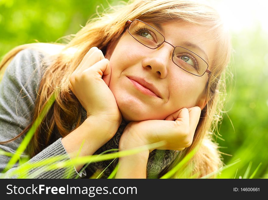 The young girl, in glasses, lays on a green grass, in park. The young girl, in glasses, lays on a green grass, in park