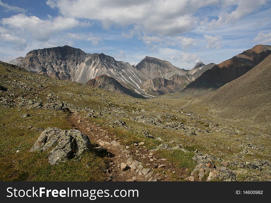 There is the mountains pathway between the stones and the big Mountains in the background