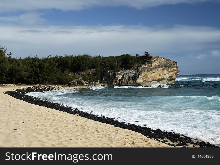 Landscape of a Kauai, HI beach with a line of lava rocks leading into the picture's focal point. Landscape of a Kauai, HI beach with a line of lava rocks leading into the picture's focal point.