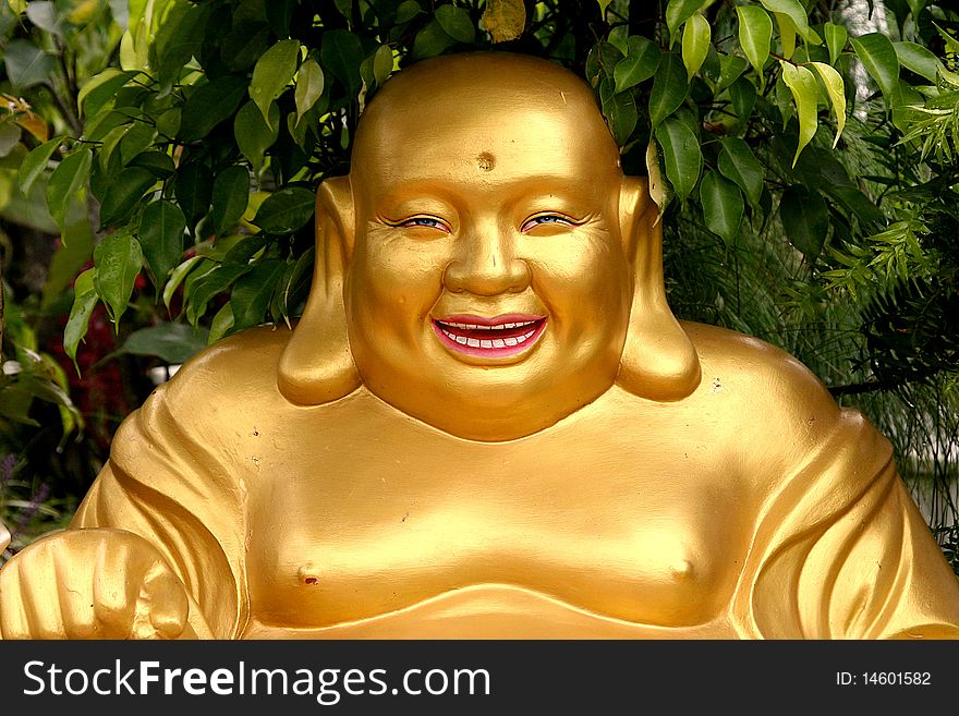 Golden statue of laughing Buddha in the garden.