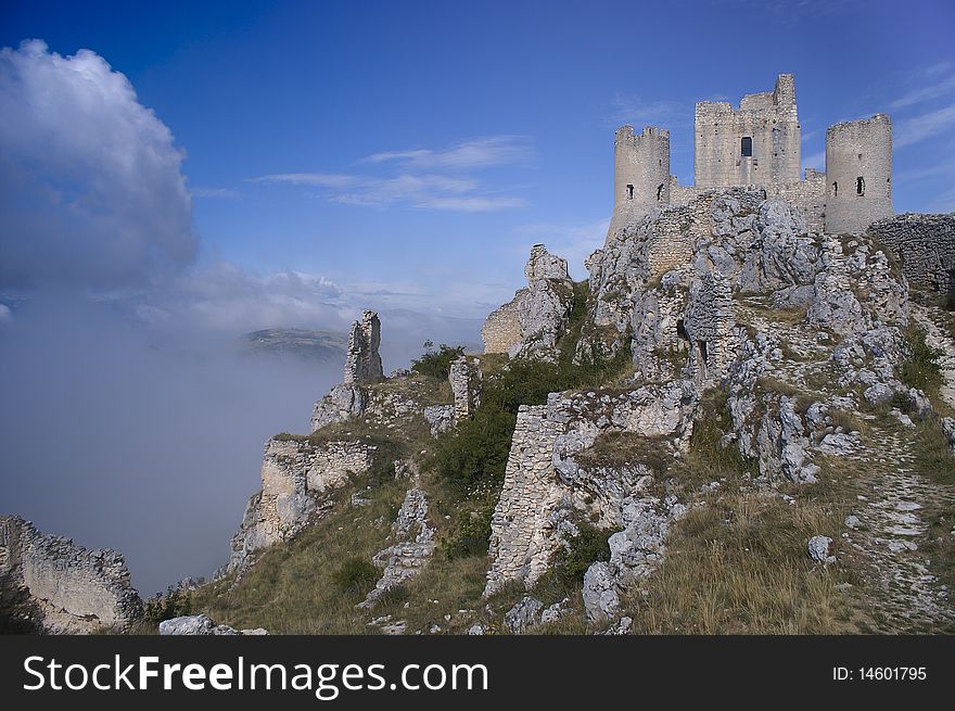 A castle in ruin on top of a mountain in central Italy.
The mountain is surrounded by clouds. A castle in ruin on top of a mountain in central Italy.
The mountain is surrounded by clouds.