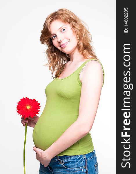 Young pregnant woman holding her hands on her tummy with red flower. Young pregnant woman holding her hands on her tummy with red flower