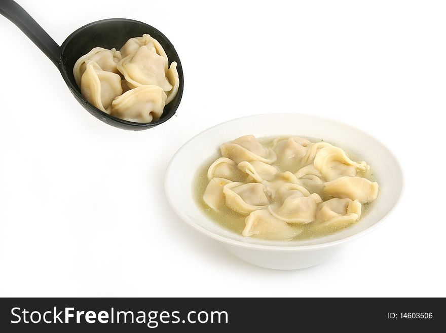 Ravioli in ladle and in plate close-up on white background