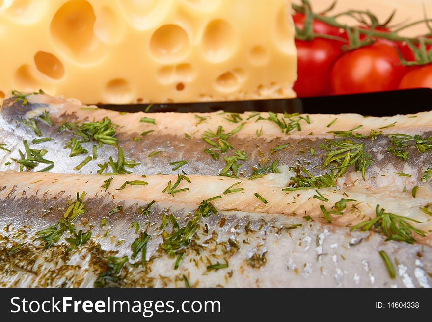 Herring on plate with piece of cheese and tomato