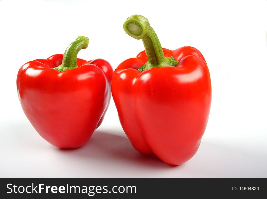 Two red pepers with green stacks on white background. Two red pepers with green stacks on white background