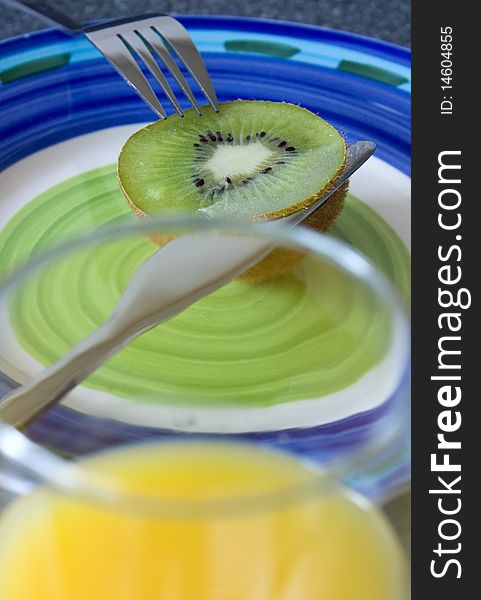 Kiwi, knife and orange juice on a plate