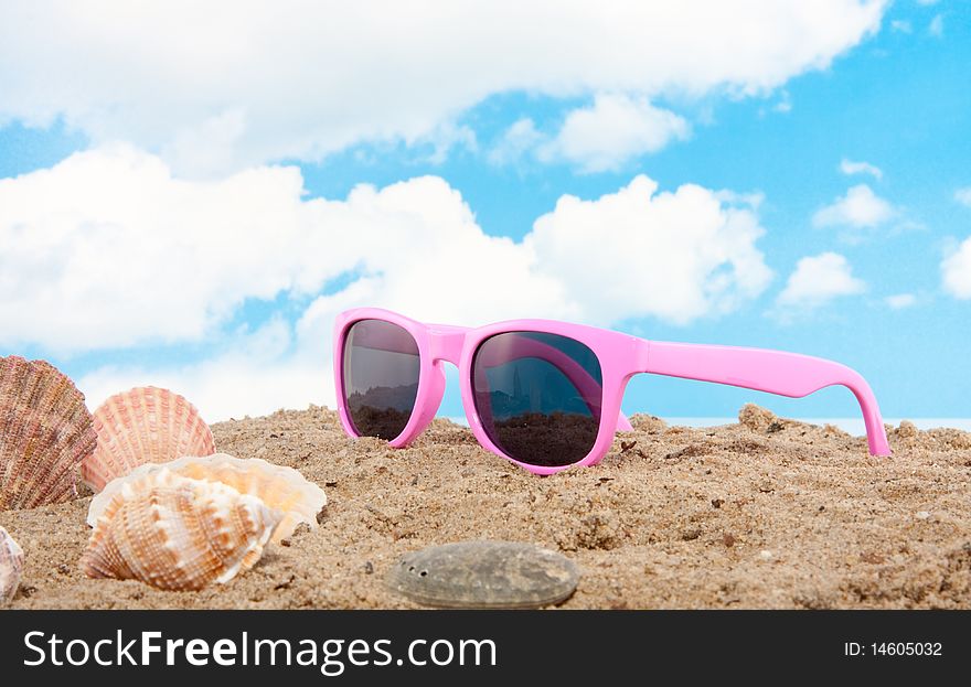 Pink sunglasses and shells on the beach