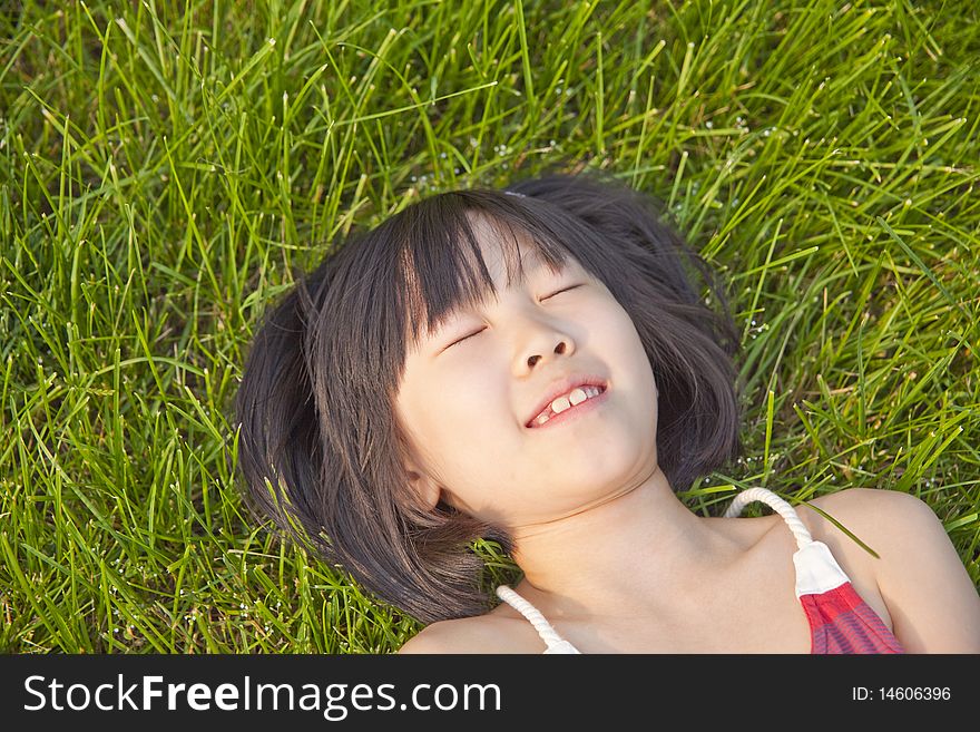The asian girl is lying on green grass in summer. The asian girl is lying on green grass in summer